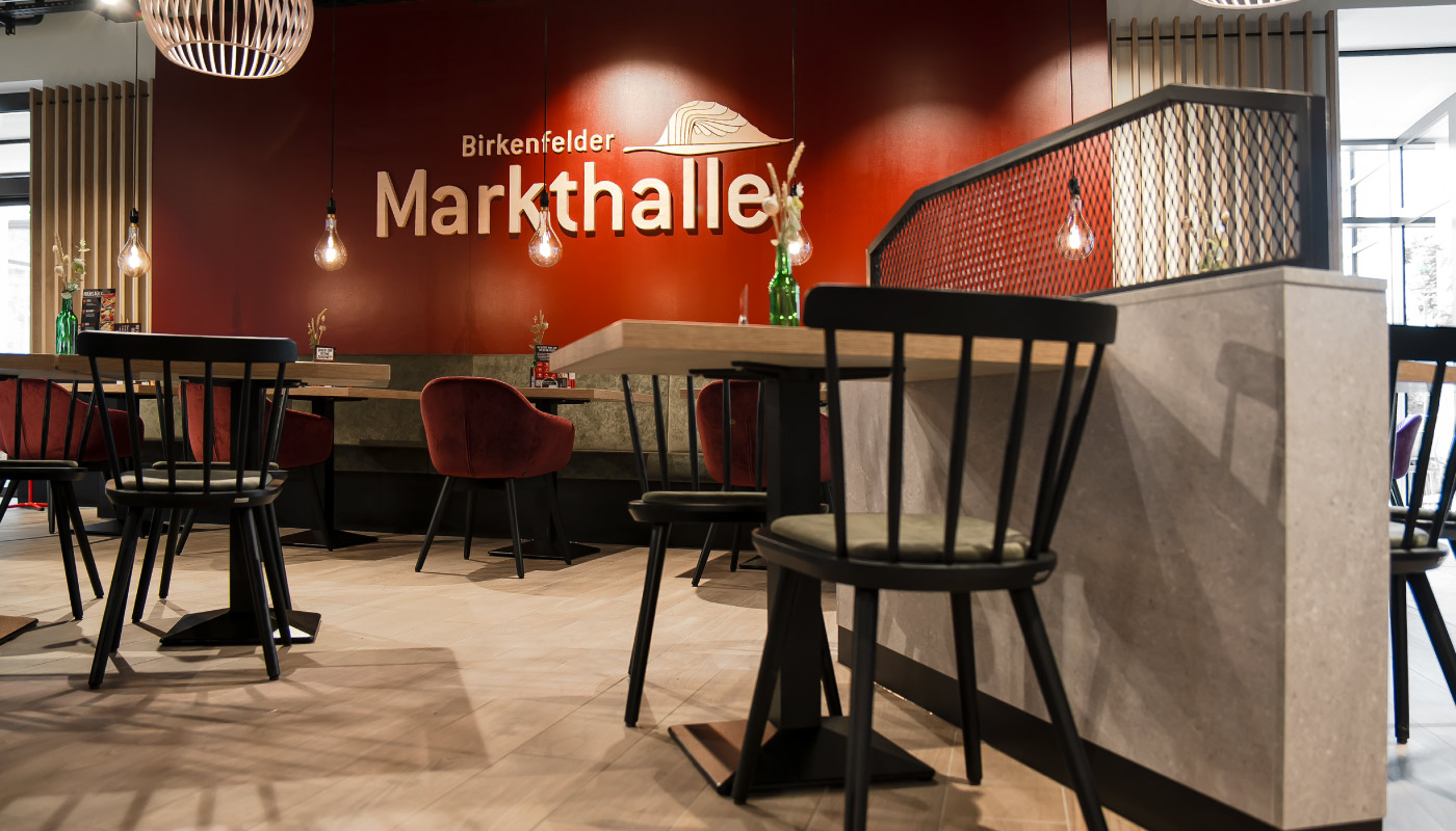 Logo der Markthalle Birkenfeld auf roter Wand im Sitzbereich